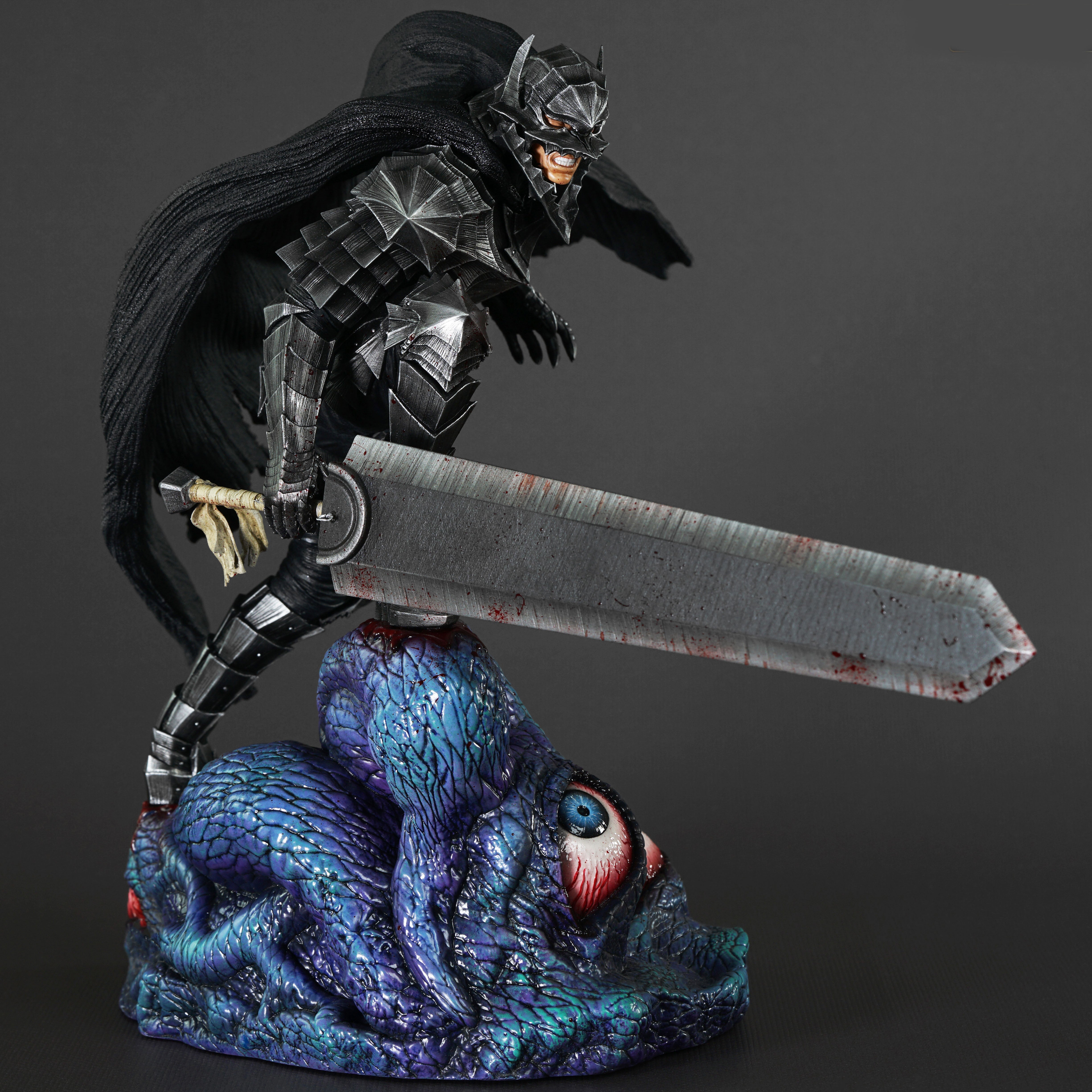 Vue 3/4 de face en plan rapproché moyen de la figurine de Guts de Berserk en armure sombre, tenant une épée ensanglantée.