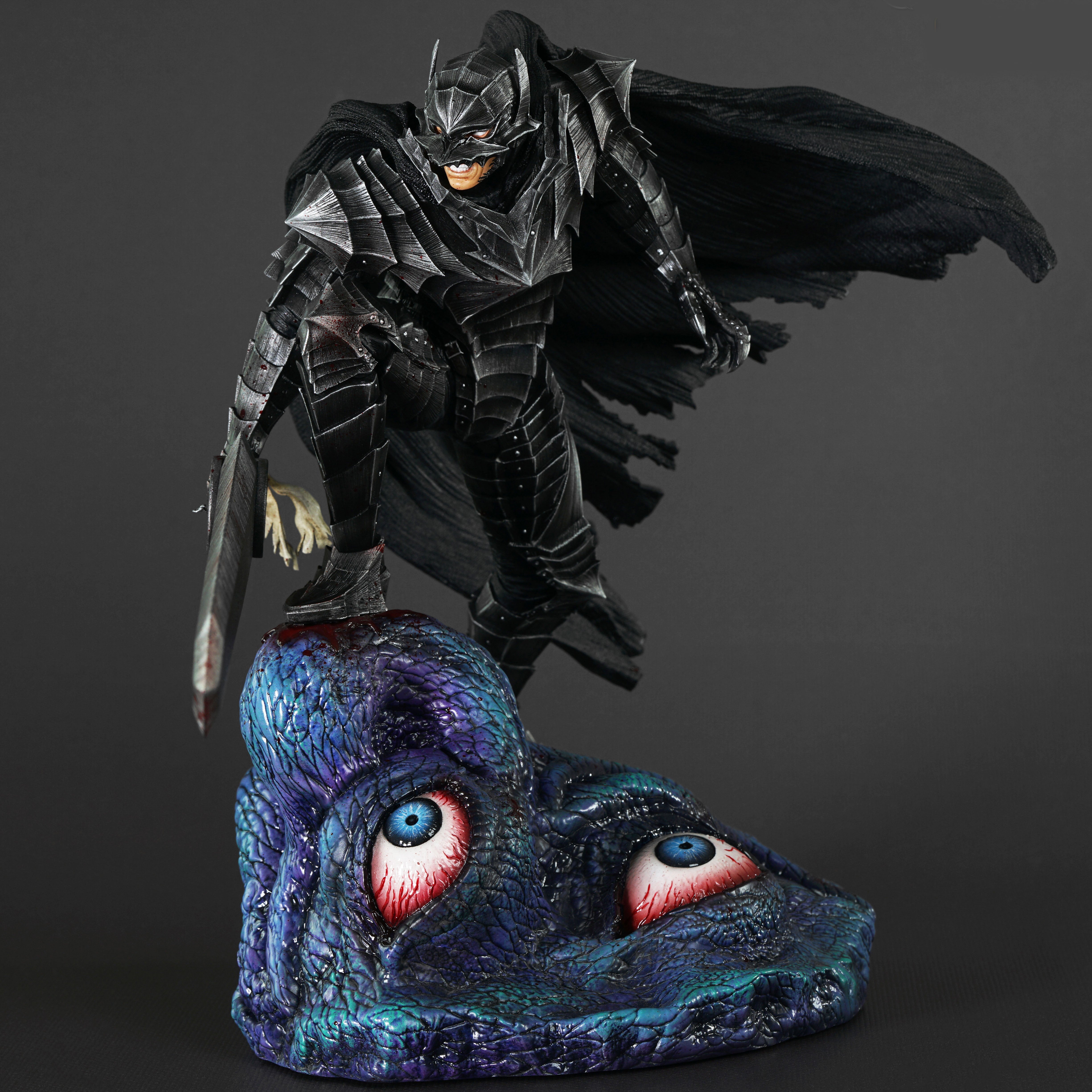Vue 3/4 de face à mi-distance de la figurine de Guts de Berserk en armure sombre, tenant une épée et posant sur une tête de créature.