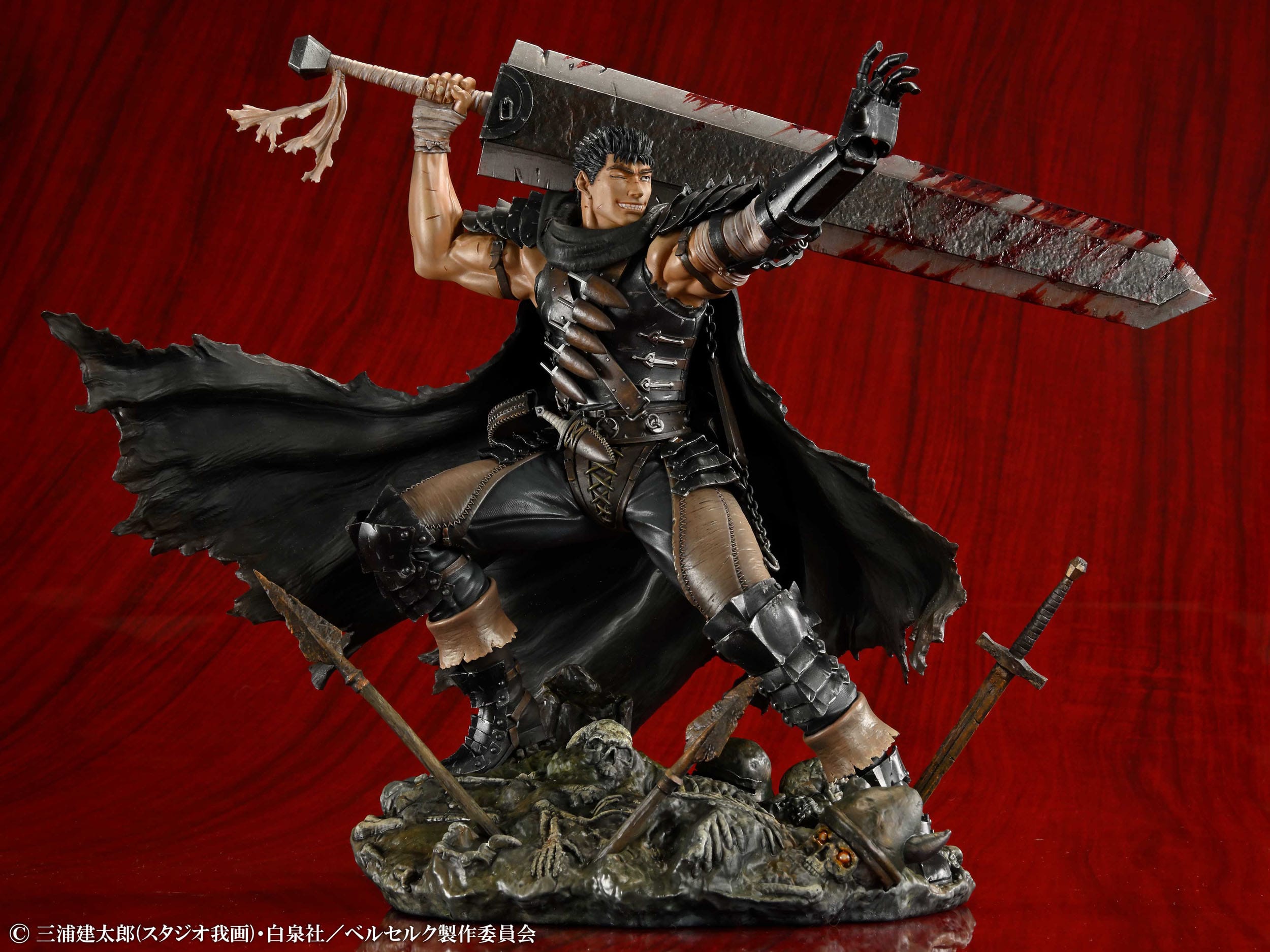 Vue 3/4 de face à mi-distance de la figurine de Guts de Berserk en tenue sombre, tenant l'épée Dragonslayer.