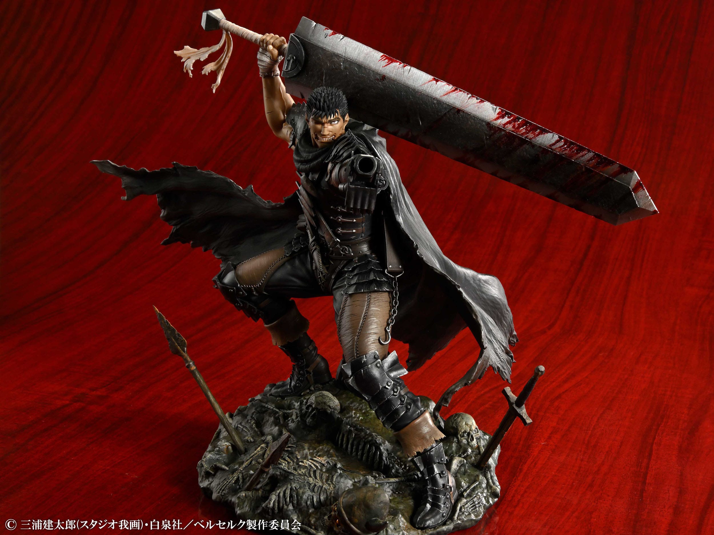 Vue 3/4 de face à mi-distance de la figurine de Guts de Berserk en armure avec une grande épée ensanglantée, sur une base avec des squelettes.