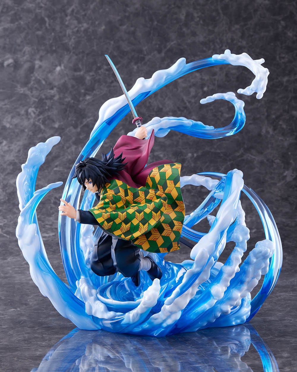 Vue 3/4 à mi-distance de la figurine de Giyu Tomioka de Demon Slayer en tenue sombre, tenant un katana à droite.