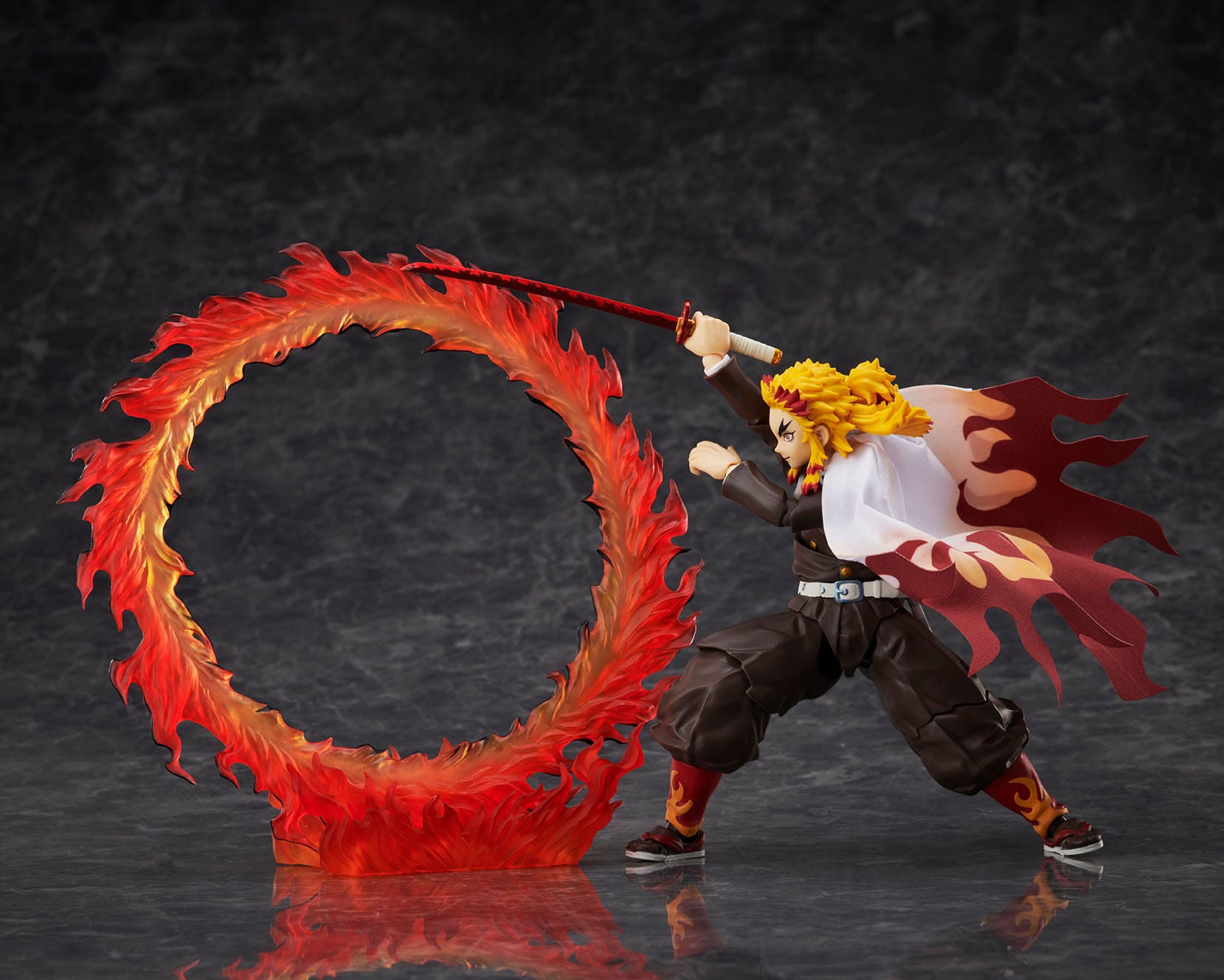 Vue 3/4 de corps entier de la figurine de Kyojuro Rengoku de Demon Slayer, en uniforme avec cape et katana, entouré de flammes.