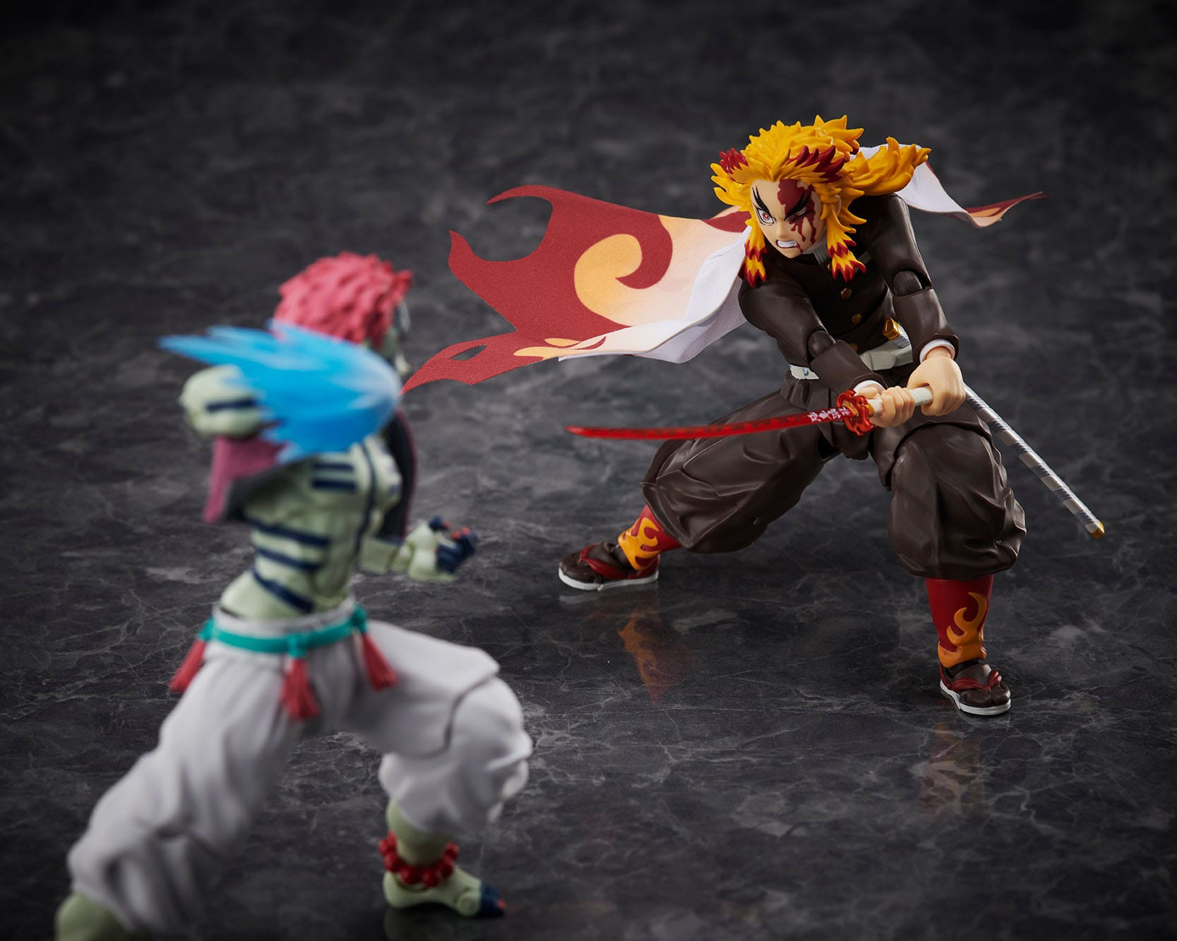 Vue 3/4 de face à mi-distance de la figurine de Kyojuro Rengoku de Demon Slayer, en uniforme avec motifs de flammes, tenant un katana.