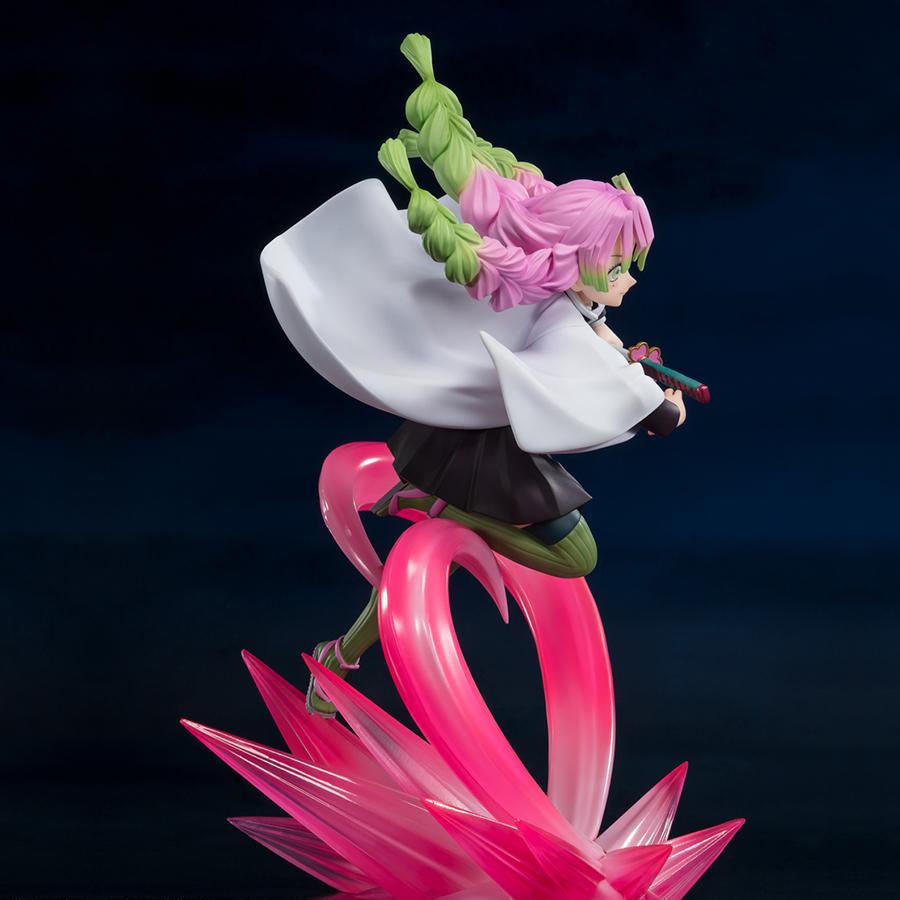 Vue 3/4 à mi-distance de la figurine de Mitsuri Kanroji de Demon Slayer, en tenue sombre et manteau blanc, tenant un katana.
