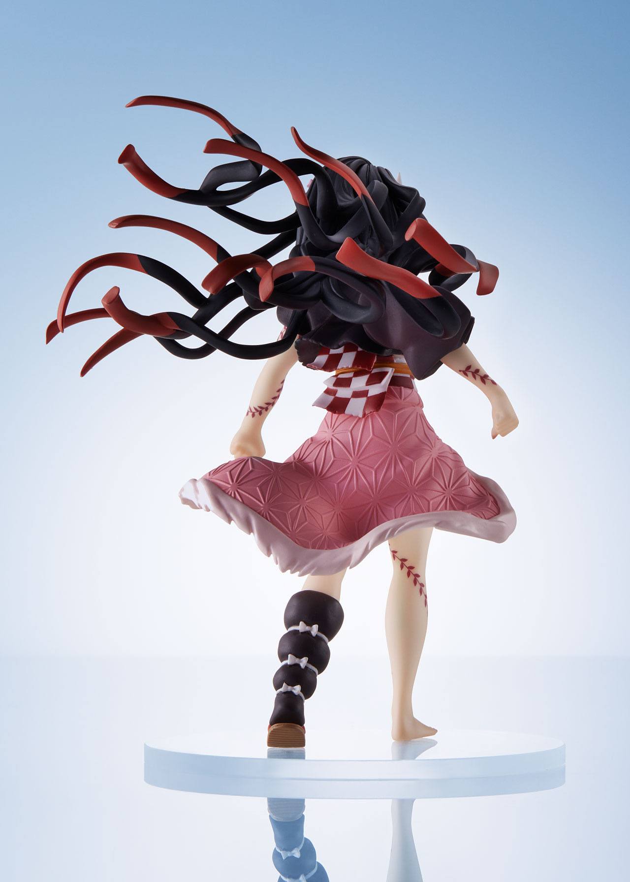 Vue 3/4 arrière à mi-distance de la figurine de Nezuko Kamado de Demon Slayer: Kimetsu no Yaiba en kimono rose, cheveux flottants.