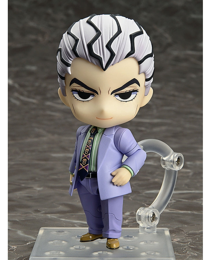 Vue 3/4 de face à mi-distance de la figurine de Yoshikage Kira de JoJo's Bizarre Adventure en costume lavande, avec un socle transparent.