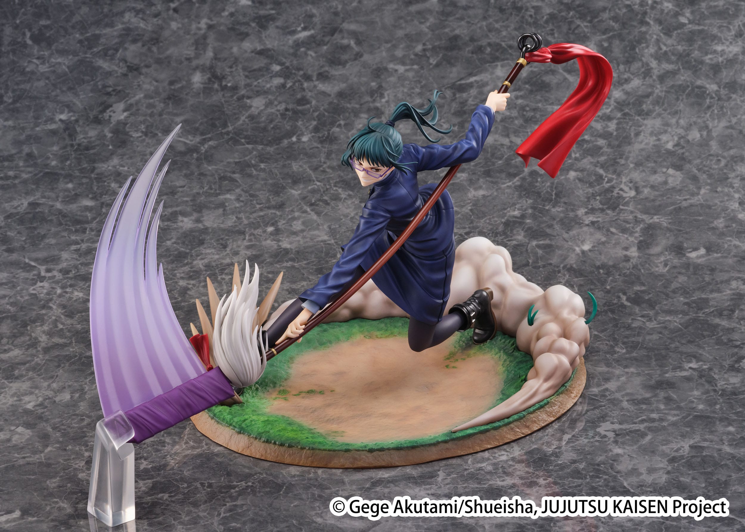 Figurine Maki Zenin de la série Jujutsu Kaisen en manteau bleu, en posture accroupie avec expression déterminée, tenant un bâton brun en mouvement. Vue 3/4 à mi-distance.
