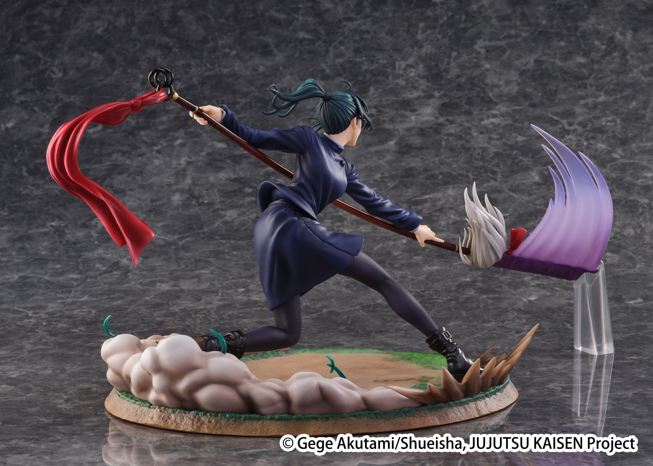 Figurine Maki Zenin de la série Jujutsu Kaisen en tenue sombre, en posture dynamique avec expression déterminée, tenant une arme longue ornée d'un ruban rouge. Vue de face à mi-distance.