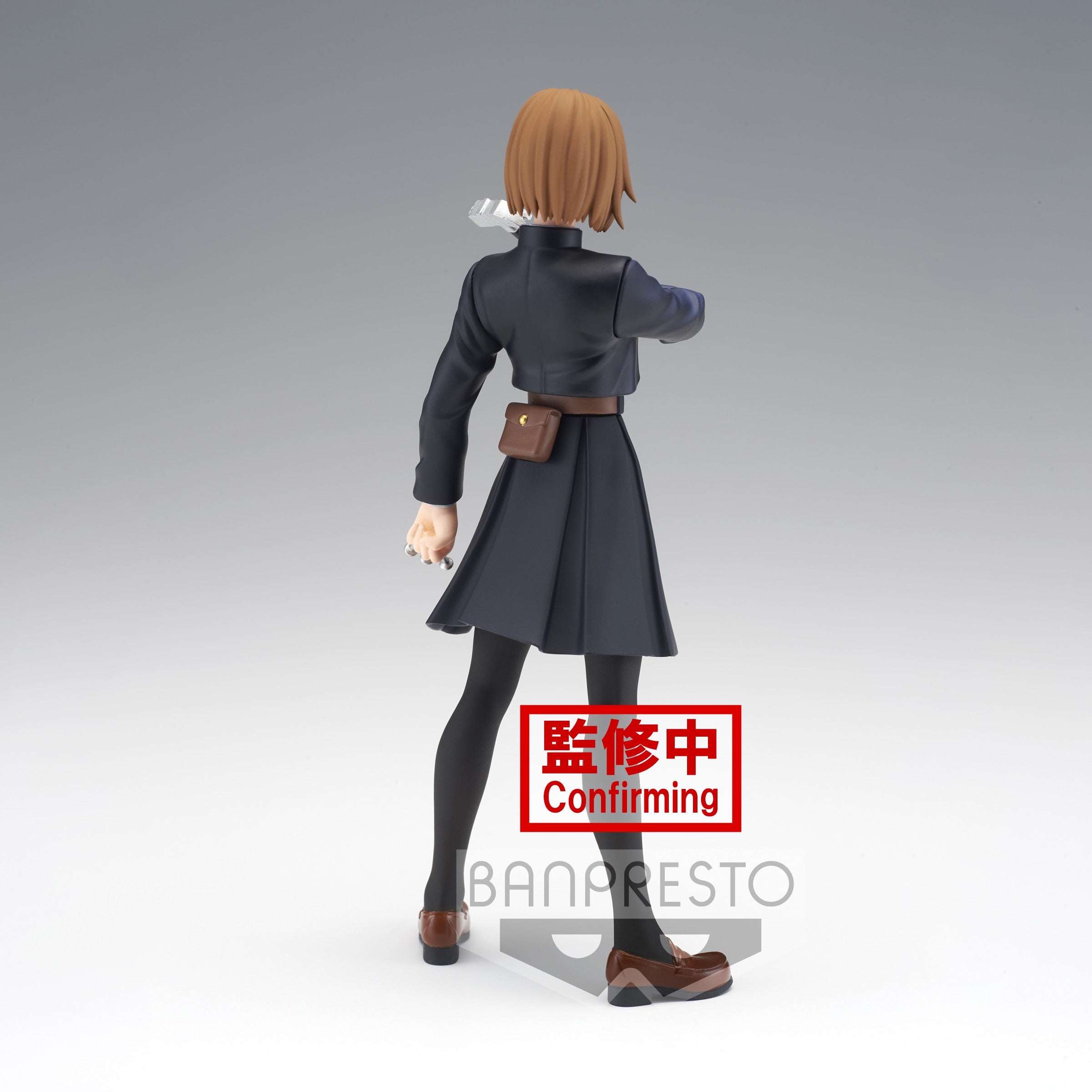 Figurine Banpresto de Nobara Kugisaki de la série Jujutsu Kaisen en manteau noir, en posture d'action avec main droite levée, vue de dos à mi-distance.