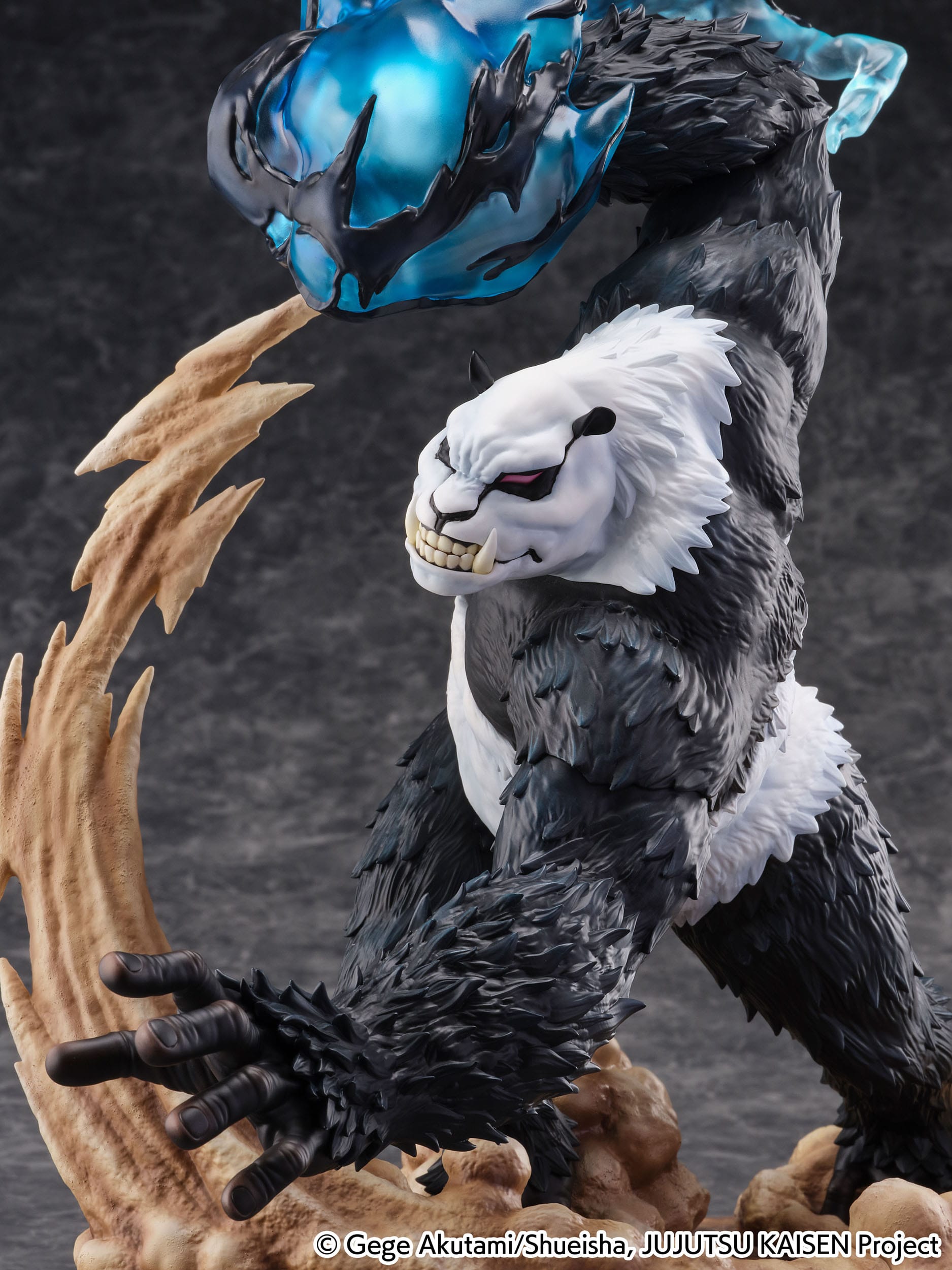 Figurine de Panda de la série Jujutsu Kaisen, en posture dynamique avec expression déterminée, tenant une masse d'énergie bleue et noire au-dessus de sa tête. Vue de face à mi-distance.