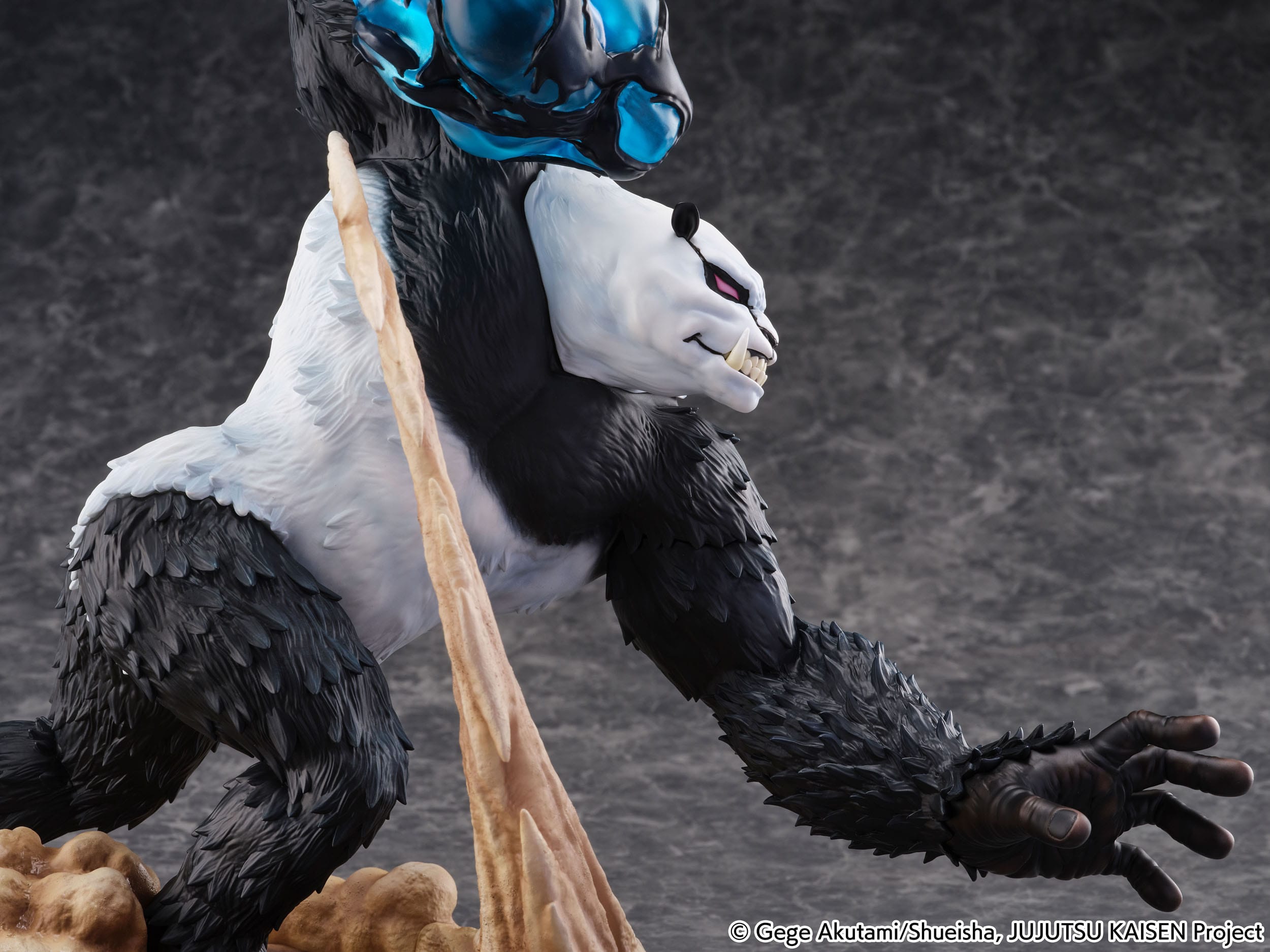 Figurine de Panda de la série Jujutsu Kaisen en fourrure noire et blanche, en posture d'attaque avec expression agressive, un élément d'énergie bleue au-dessus de sa tête. Vue de face à mi-distance.