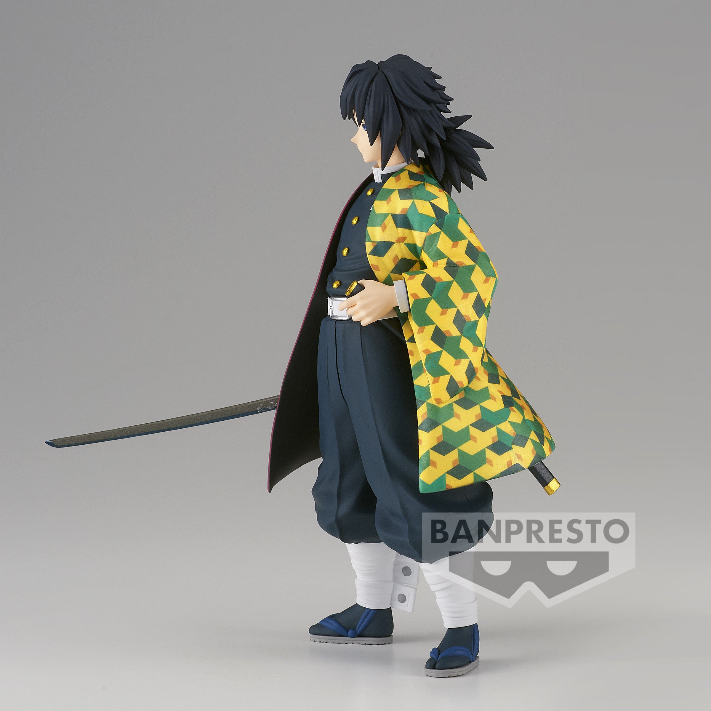 Vue 3/4 de mi-distance de la figurine de Giyu Tomioka de Demon Slayer: Kimetsu no Yaiba, en uniforme avec katana derrière.