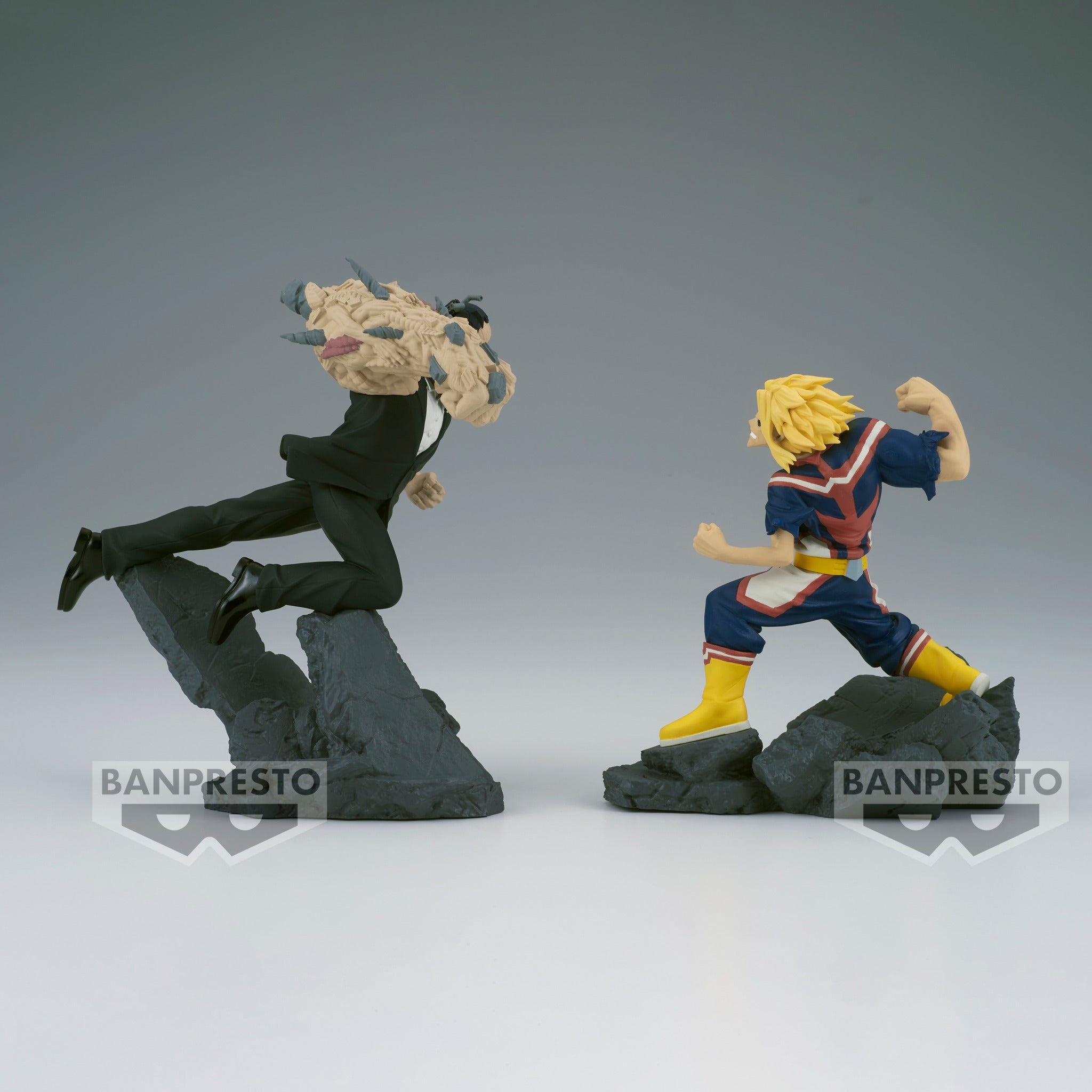 Vue de profil à mi-distance de la figurine d'All Might et d'un antagoniste de My Hero Academia en costumes distincts, All Might pose avec poigne.