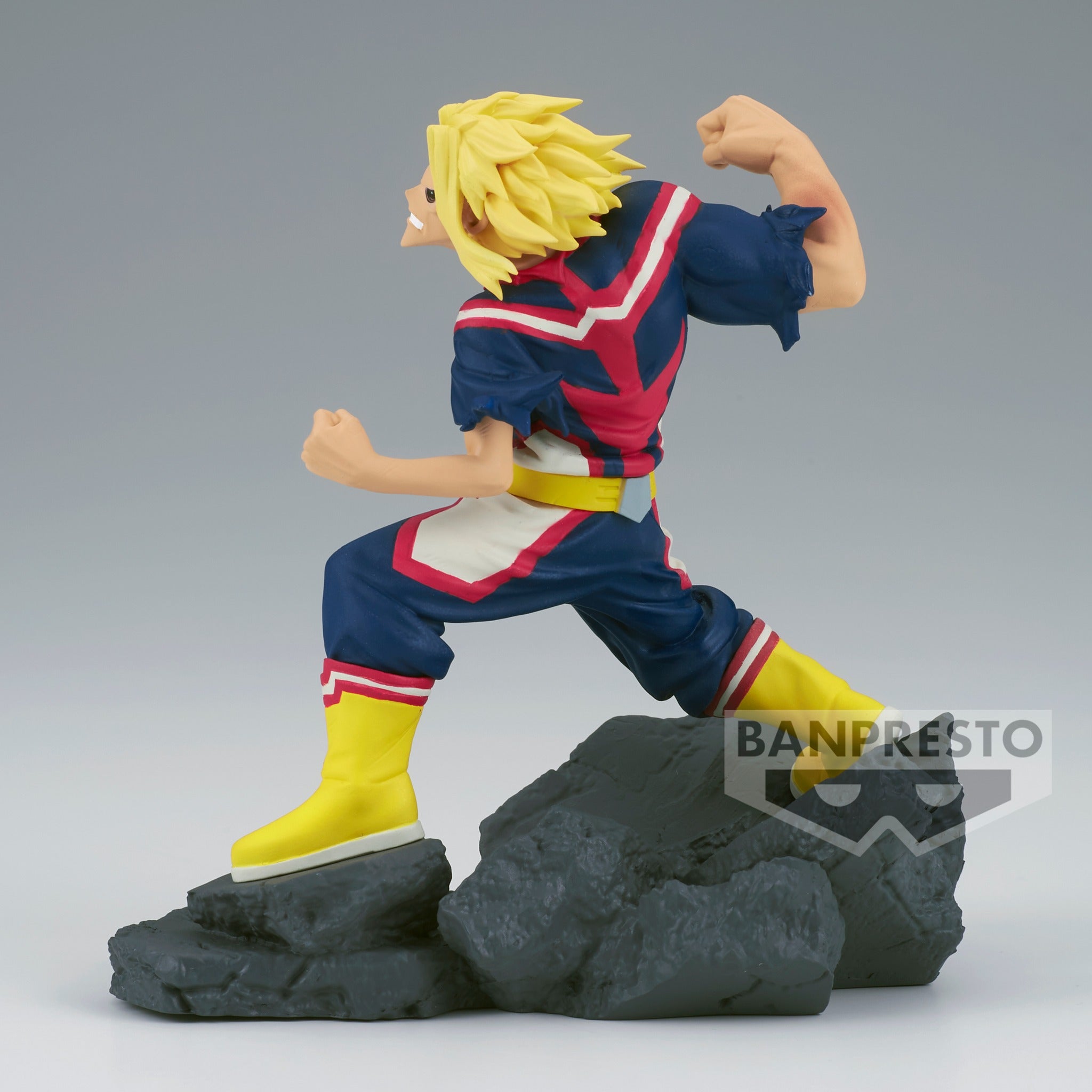 Vue de profil à distance complète de la figurine  d'All Might de My Hero Academia en costume de héros rouge, blanc et bleu, poing levé.