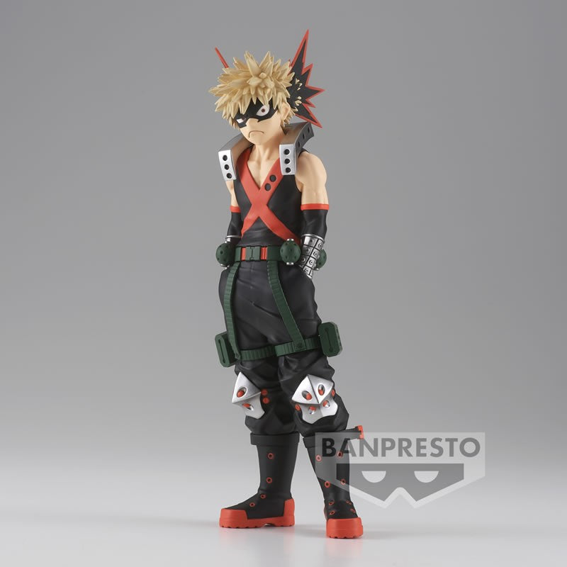 Vue 3/4 de face à pleine longueur de la figurine de Katsuki Bakugo de My Hero Academia en costume de héros noir et orange, avec gantelets explosifs.