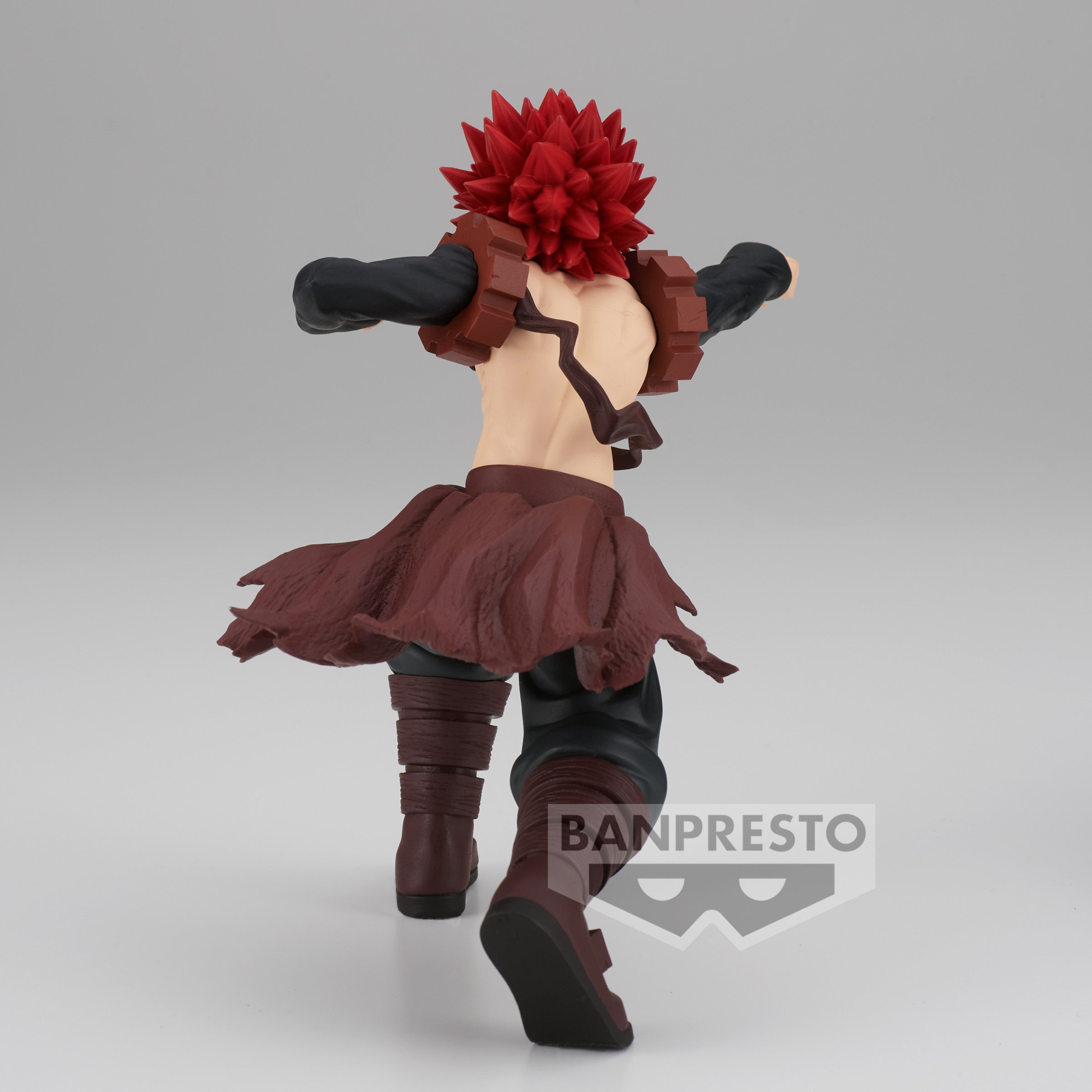 Vue 3/4 de dos à mi-distance de la figurine de Eijiro Kirishima de My Hero Academia, torse nu et en position dynamique, vêtu d'une tenue en cuir brun déchirée.