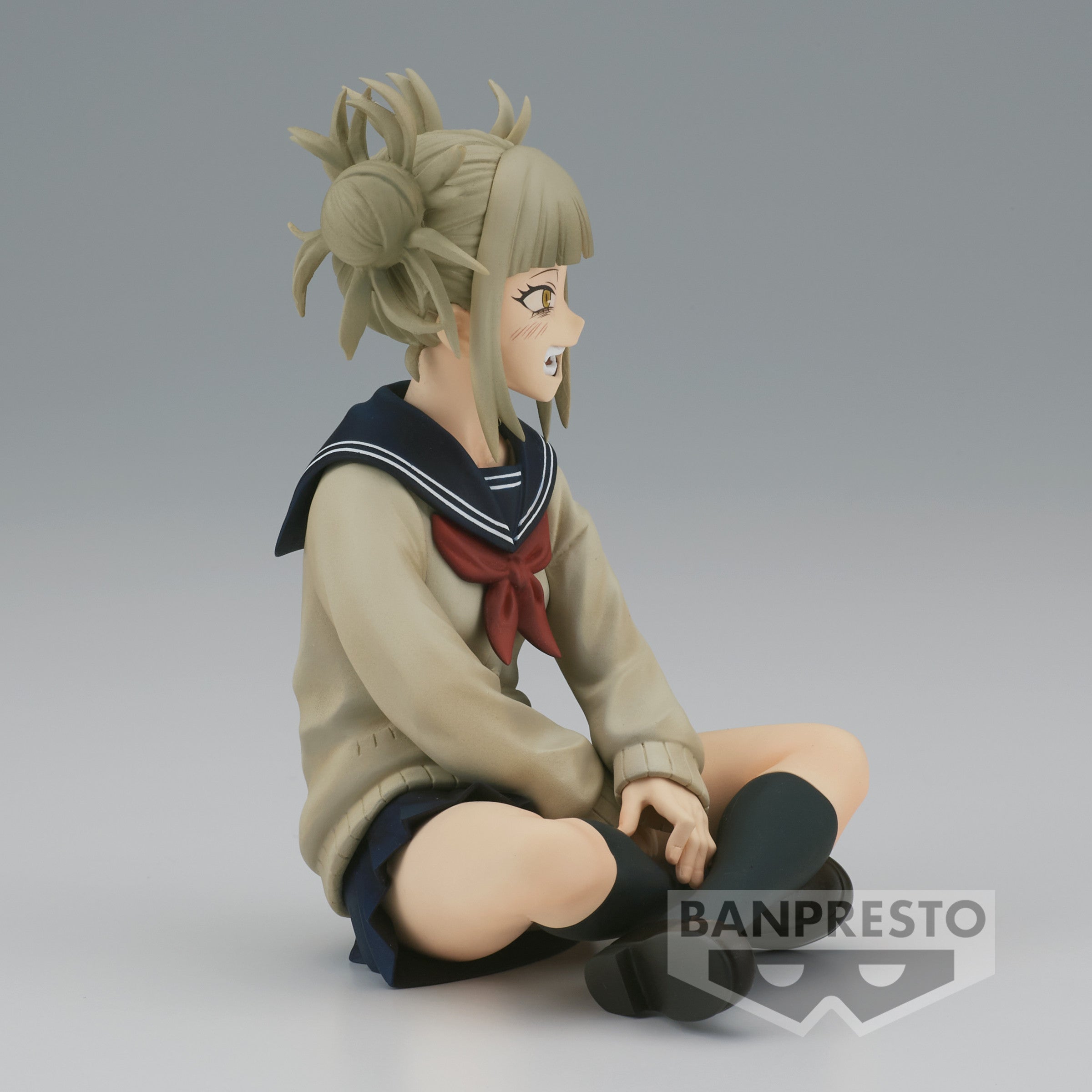 Vue de profil à mi-distance de la figurine  de Himiko Toga de My Hero Academia en uniforme scolaire, assise les jambes croisées, avec un léger sourire.