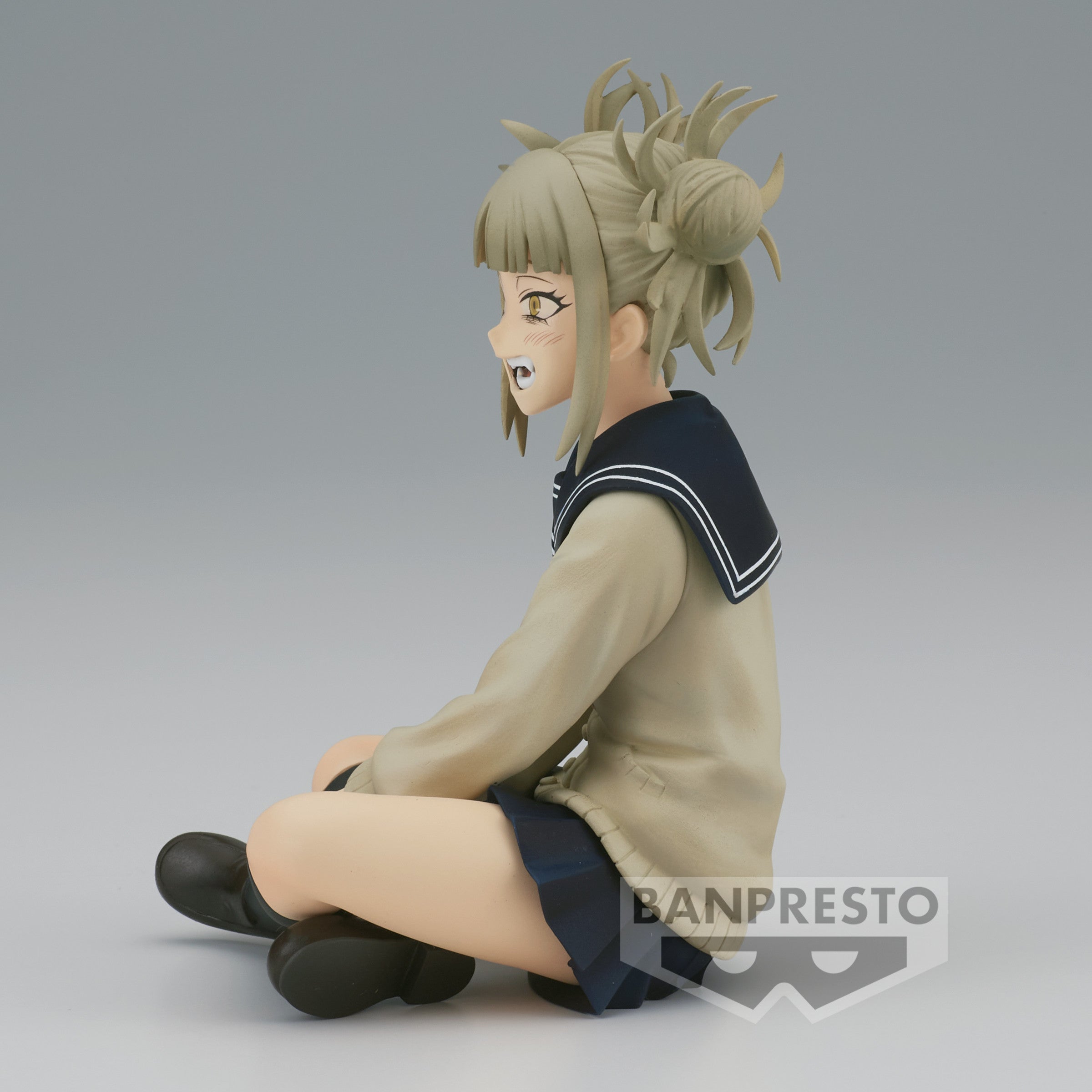 Vue 3/4 de face à mi-distance de la figurine Prize de Himiko Toga de My Hero Academia en uniforme scolaire, assise avec un sourire malicieux.