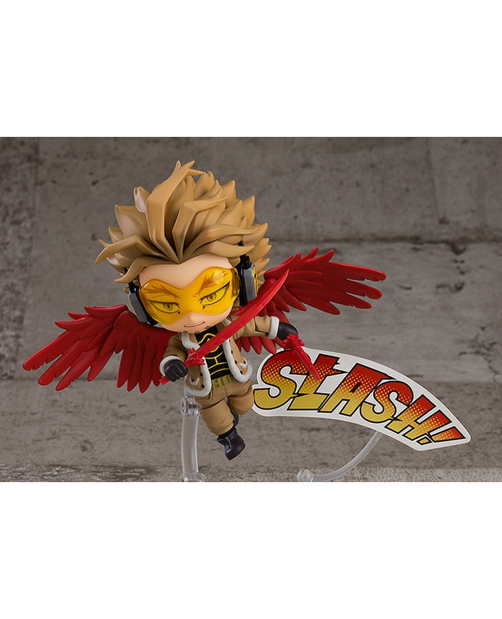 Vue en diagonale à mi-distance de la figurine Nendoroid de Hawks de My Hero Academia en veste beige, avec ailes de plumes rouges, tenant une arme.
