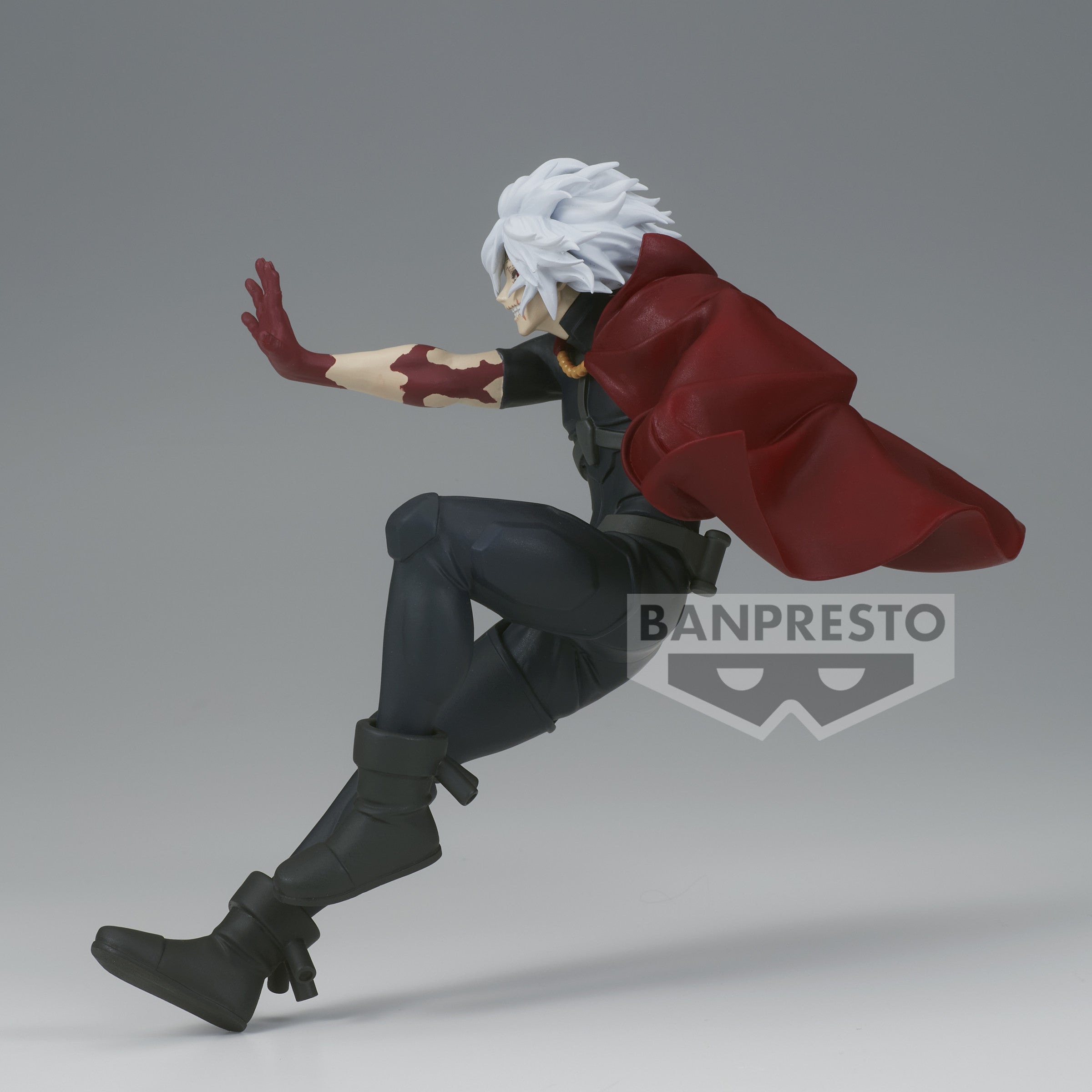 Vue de profil à mi-distance de la figurine  de Tomura Shigaraki de My Hero Academia en costume noir avec une cape rouge, en posture dynamique.