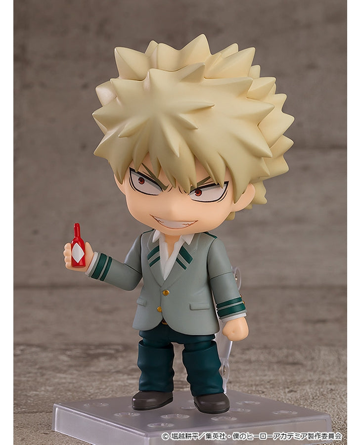 Vue 3/4 de face à mi-distance de la figurine Nendoroid de Katsuki Bakugo de My Hero Academia en uniforme scolaire, tenant un petit objet rouge.