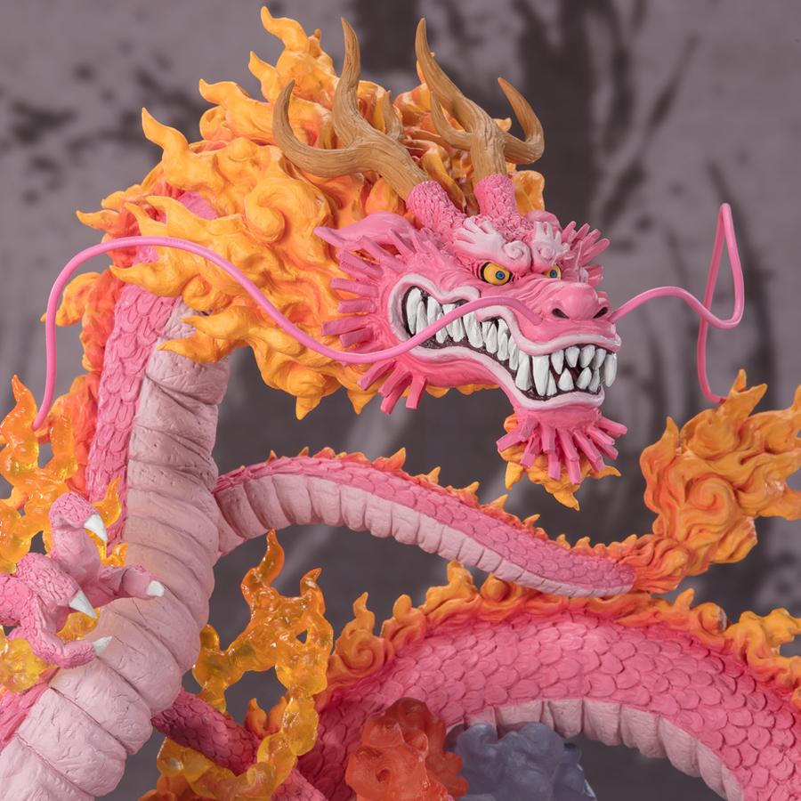 Figurine de Momonosuke Kozuki en PVC, représentant le personnage en pose dynamique, avec des écailles roses et des nuages dorés entourant ses pattes. Dimensions de 28,5 cm, fabriquée par TAMASHII NATIONS.