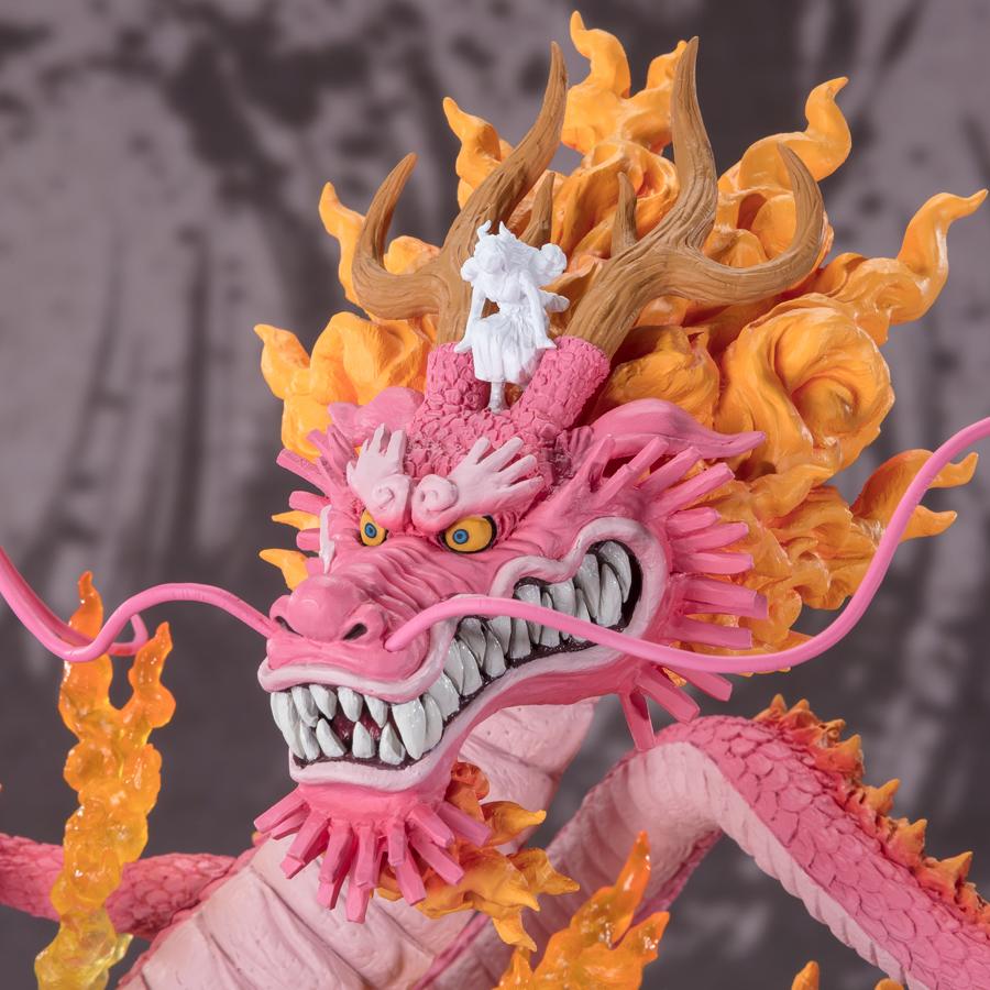 Figurine de Momonosuke Kozuki en PVC, représentant le personnage en pose dynamique, avec des écailles roses et des nuages dorés entourant ses pattes. Dimensions de 28,5 cm, fabriquée par TAMASHII NATIONS.