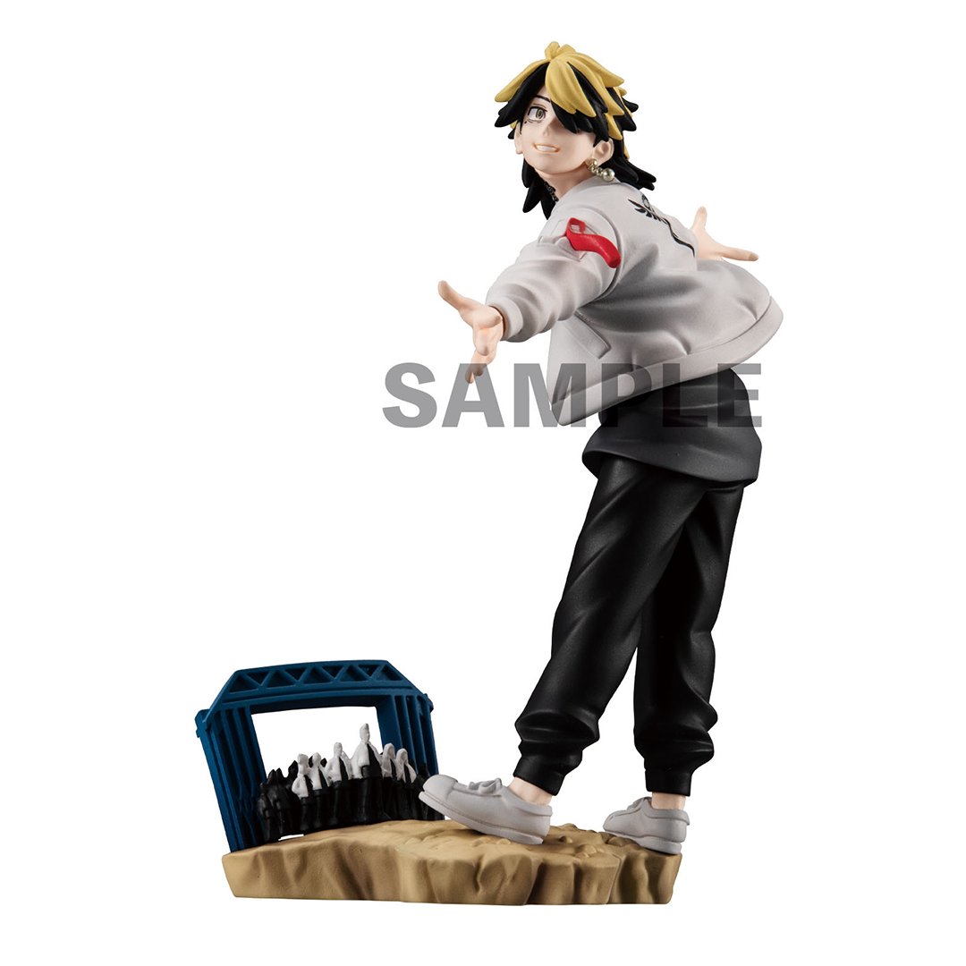 Vue 3/4 arrière à mi-distance de la figurine de Toman de Tokyo Revengers en veste claire avec des accents rouges, posée sur un stand avec des figurines miniatures.
