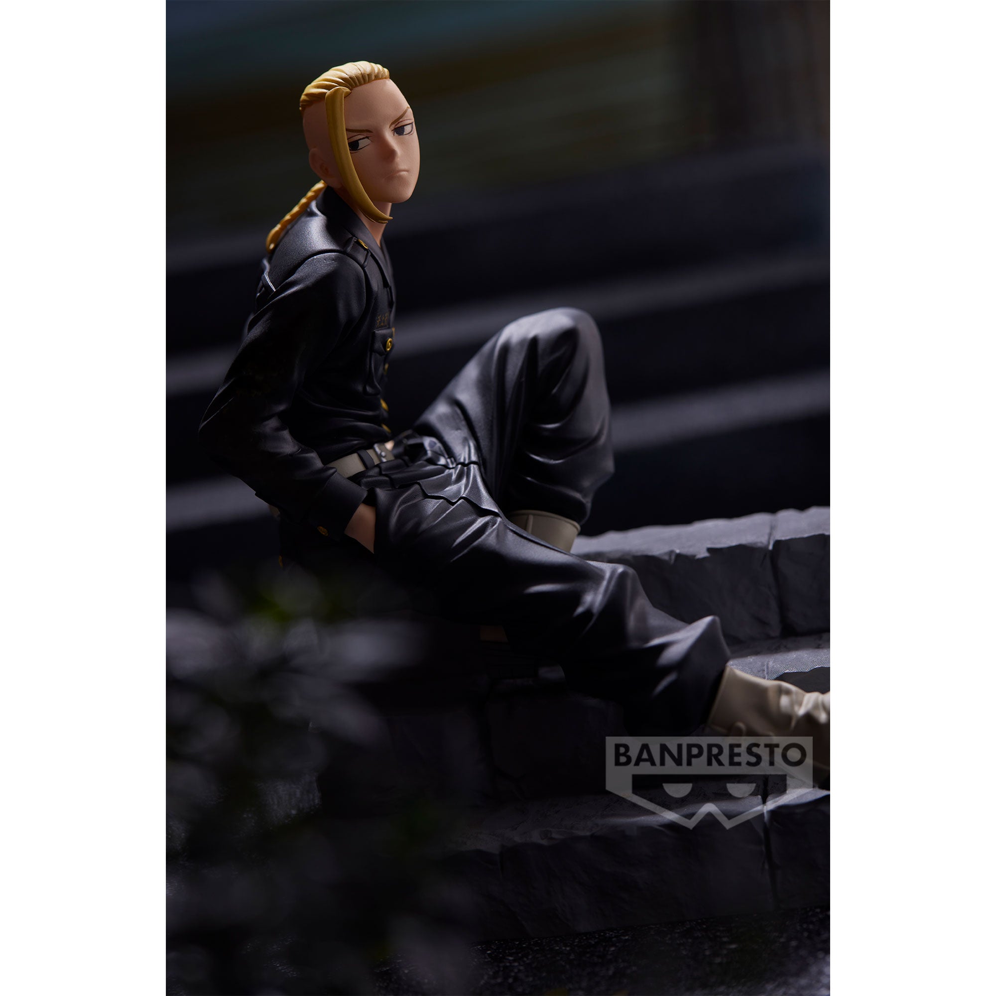 Vue 3/4 de face à mi-distance de la figurine de Ken Ryuguji de Tokyo Revengers en uniforme militaire noir, assis sur des escaliers.
