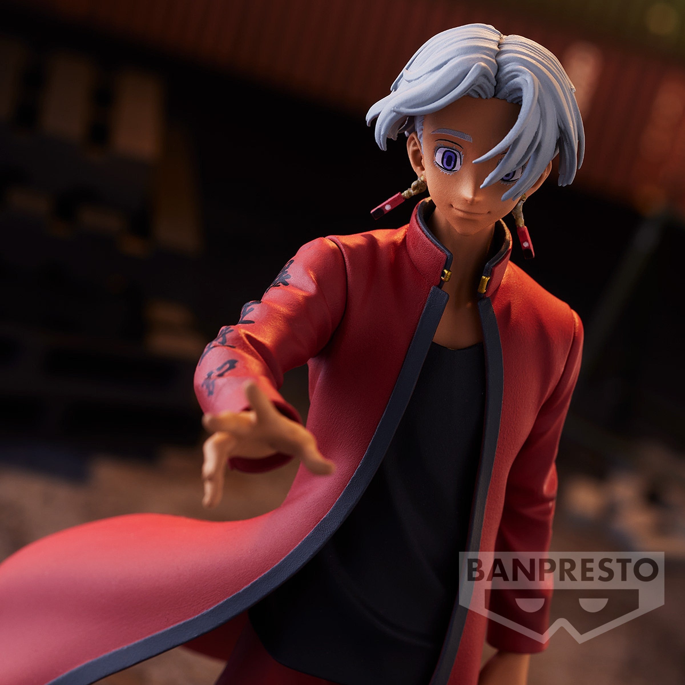 Vue 3/4 de face à mi-distance de la figurine d'Izana Kurokawa de Tokyo Revengers en manteau rouge, avec des boucles d'oreilles rouges.