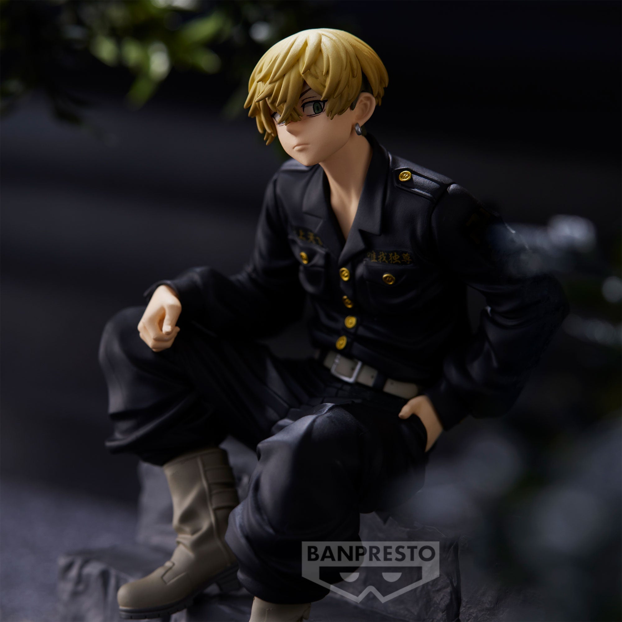 Vue 3/4 de face à mi-distance de la figurine de Matsuno Chifuyu de Tokyo Revengers en uniforme noir, assis sur une surface rocheuse.