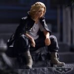 Vue 3/4 de face à mi-distance de la figurine de Manjiro Sano de Tokyo Revengers en manteau noir, assis et pensif.