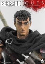 Vue 3/4 de face à mi-distance de la figurine de Guts de Berserk en manteau noir avec une épée, sans emballage visible.