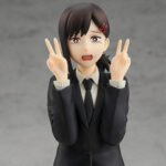 Vue 3/4 de face en plan rapproché de la figurine Pop Up Parade de Kobeni Higashiyama de Chainsaw Man en costume noir, avec expression alarmée, faisant un signe de paix.