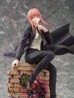 Vue 3/4 de face à mi-distance de la figurine de Makima de Chainsaw Man en costume noir, assise sur des briques avec graffiti.