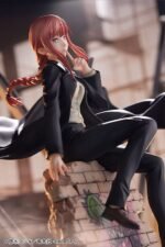 Vue 3/4 de face à mi-distance de la figurine de Makima de Chainsaw Man en costume noir, assise sur des briques.