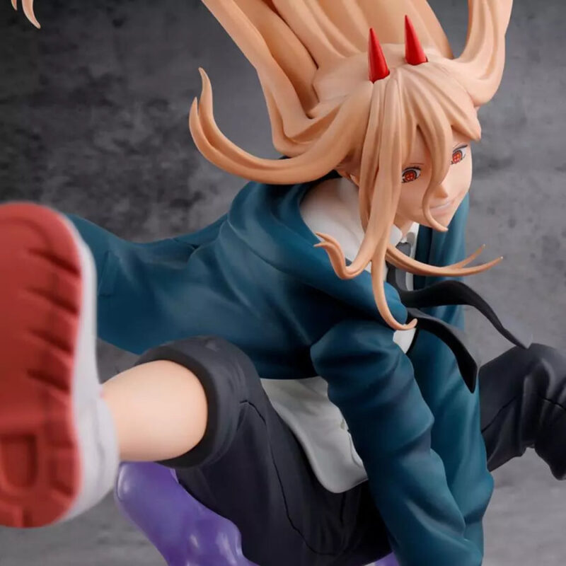 Vue de haut à angle dynamique avec plan rapproché moyen de la figurine de Power de Chainsaw Man en veste bleue, avec des cornes rouges.