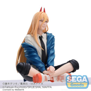 Vue 3/4 de face à mi-distance de la figurine de Power de Chainsaw Man, assise avec un sourire, portant un haut blanc et une cravate noire.