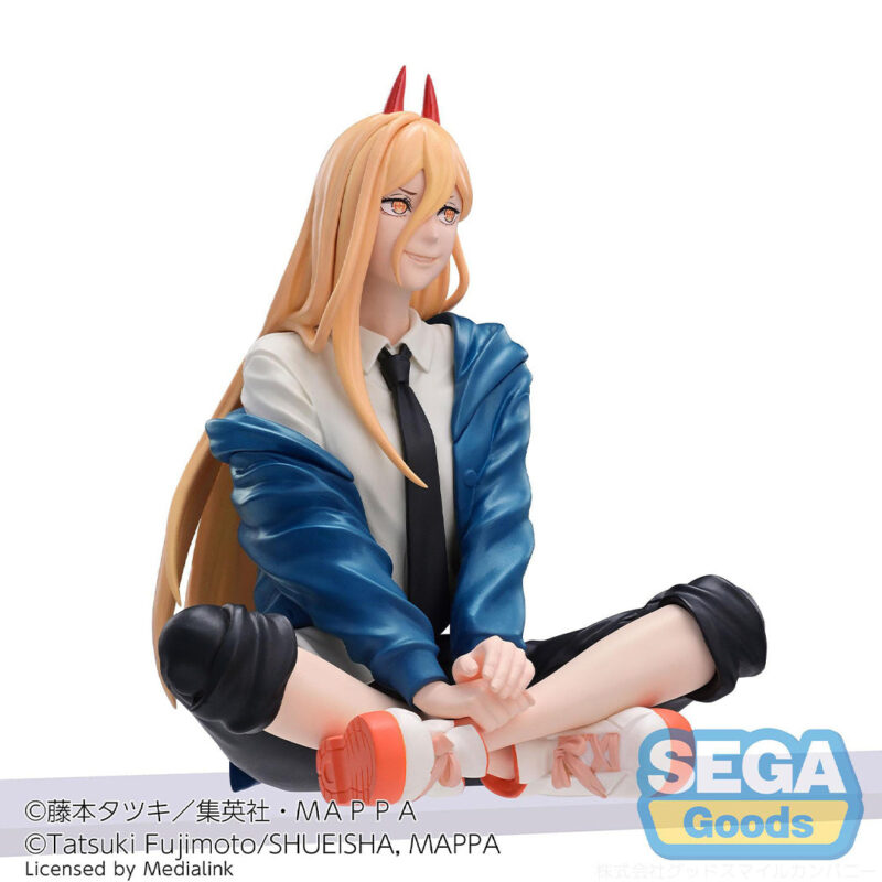 Vue 3/4 de face à mi-distance de la figurine de Power de Chainsaw Man, assise avec un sourire, portant un haut blanc et une cravate noire.