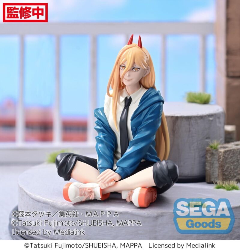 Vue 3/4 de face à mi-distance de la figurine de Power de Chainsaw Man, assise avec un uniforme scolaire, souriante, avec des cornes.