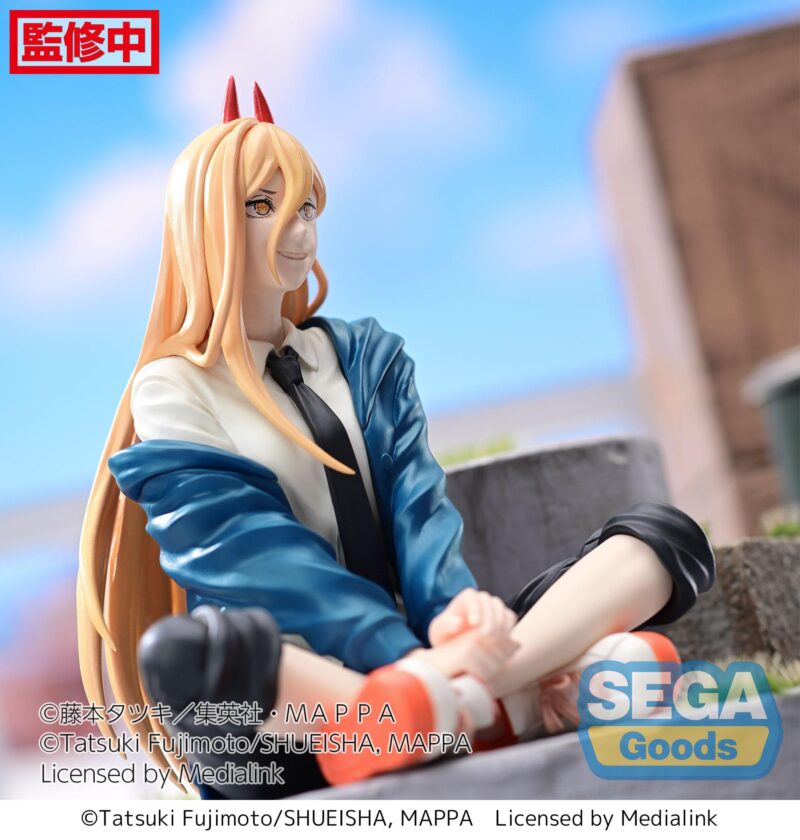 Vue 3/4 de face à mi-distance de la figurine SEGA Goods de Power de Chainsaw Man, assise, portant une chemise blanche, une cravate noire, une veste bleue, un pantalon noir et des chaussures rouges, avec des cornes orange/rouge.