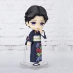 Vue 3/4 à mi-distance de la figurine de Tamayo de Demon Slayer: Kimetsu no Yaiba en kimono bleu, touchant son menton.