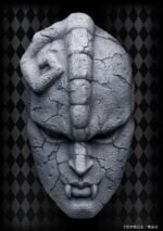 Vue de face en plan rapproché de la Stone Mask de JoJo's Bizarre Adventure: Phantom Blood, avec des fissures et des dents proéminentes.