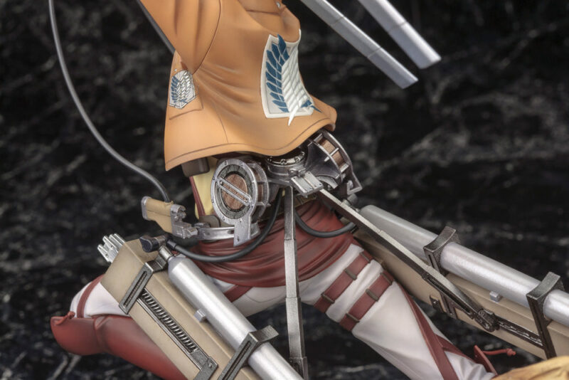Vue 3/4 latérale en plan moyen de la figurine Eren Yeager de Shingeki no Kyojin en uniforme de la Survey Corps, prêt au combat, équipé de l'Équipement de manœuvre tridimensionnelle.