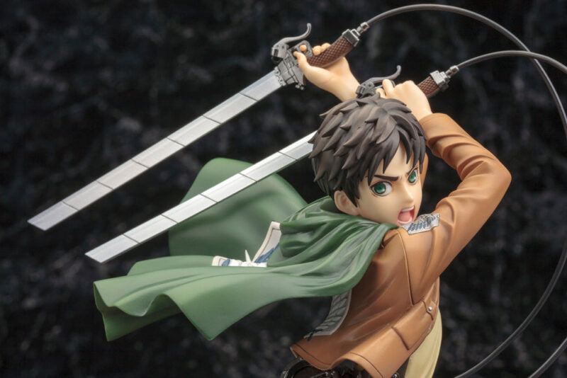 Vue 3/4 de face à mi-distance de la figurine ARTFX J d'Eren Yeager d'Attack on Titan en uniforme des Corps d'Exploration, tenant des épées.