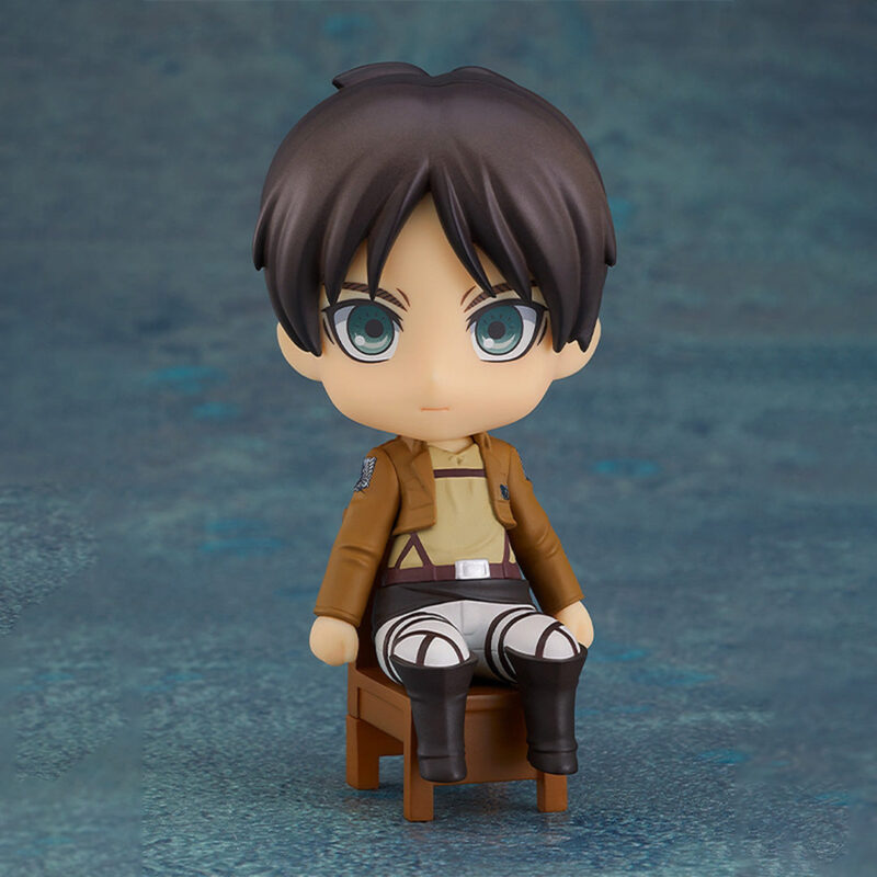 Vue de face à mi-distance de la figurine Nendoroid d'Eren Yeager de Shingeki no Kyojin en uniforme des Corps d'exploration, assis sur une petite chaise.