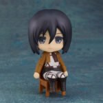 Vue 3/4 de face à mi-distance de la figurine Nendoroid de Mikasa Ackerman d'Attack on Titan en uniforme militaire, assise.