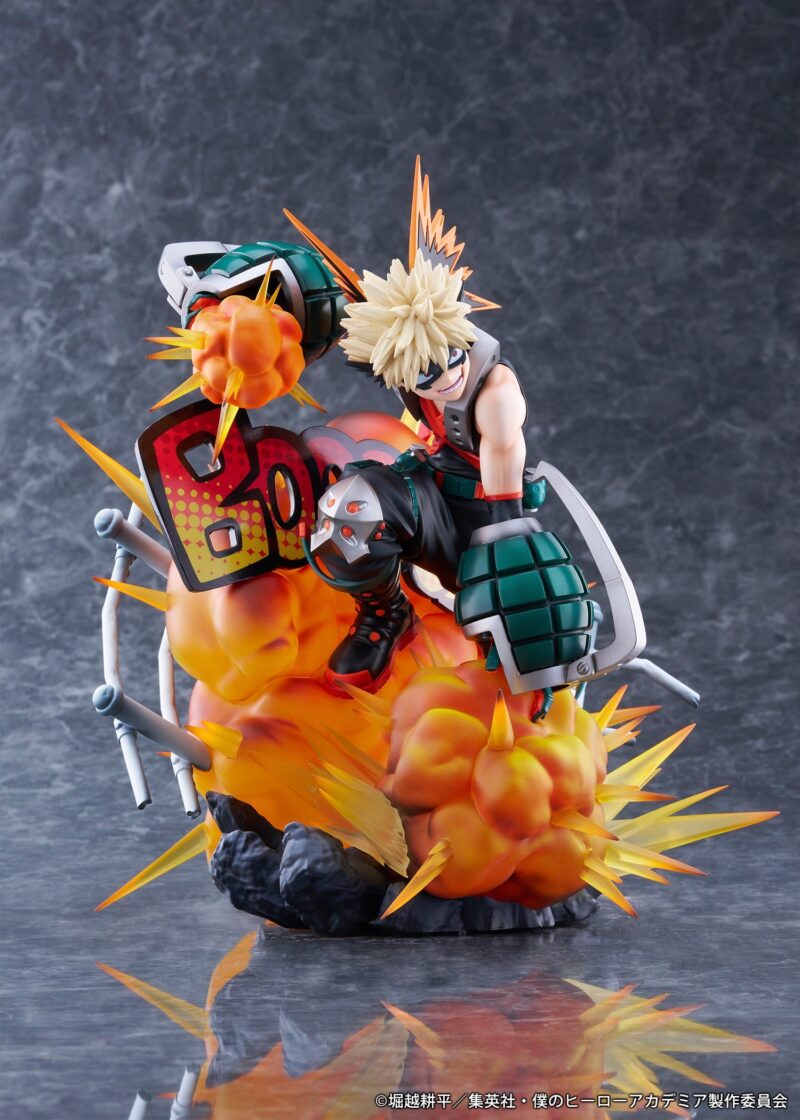 Vue 3/4 de face à mi-distance de la figurine de Katsuki Bakugo de My Hero Academia en tenue tactique, tenant des gantelets avec effets d'explosion en arrière-plan.