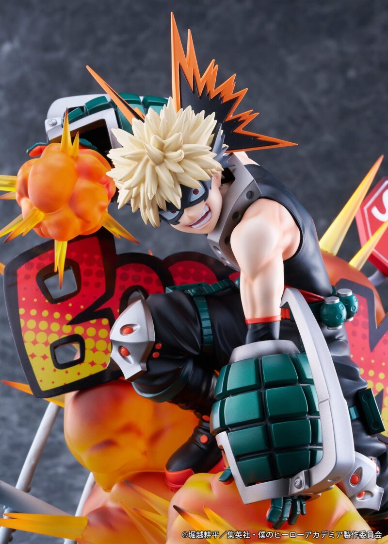 Vue 3/4 de face à mi-distance de la figurine de Katsuki Bakugo de My Hero Academia en costume noir sans manches avec accents verts, tenant des grenades à main sur les gantelets.