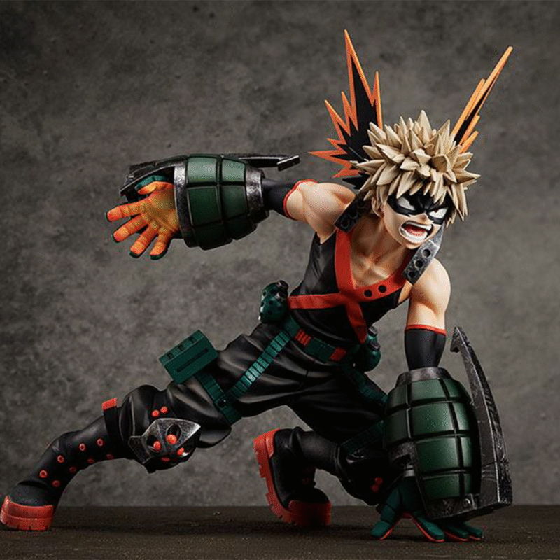 Vue dynamique à mi-distance de la figurine de Katsuki Bakugo de Boku no Hero Academia en costume noir avec accents orange, en posture accroupie.